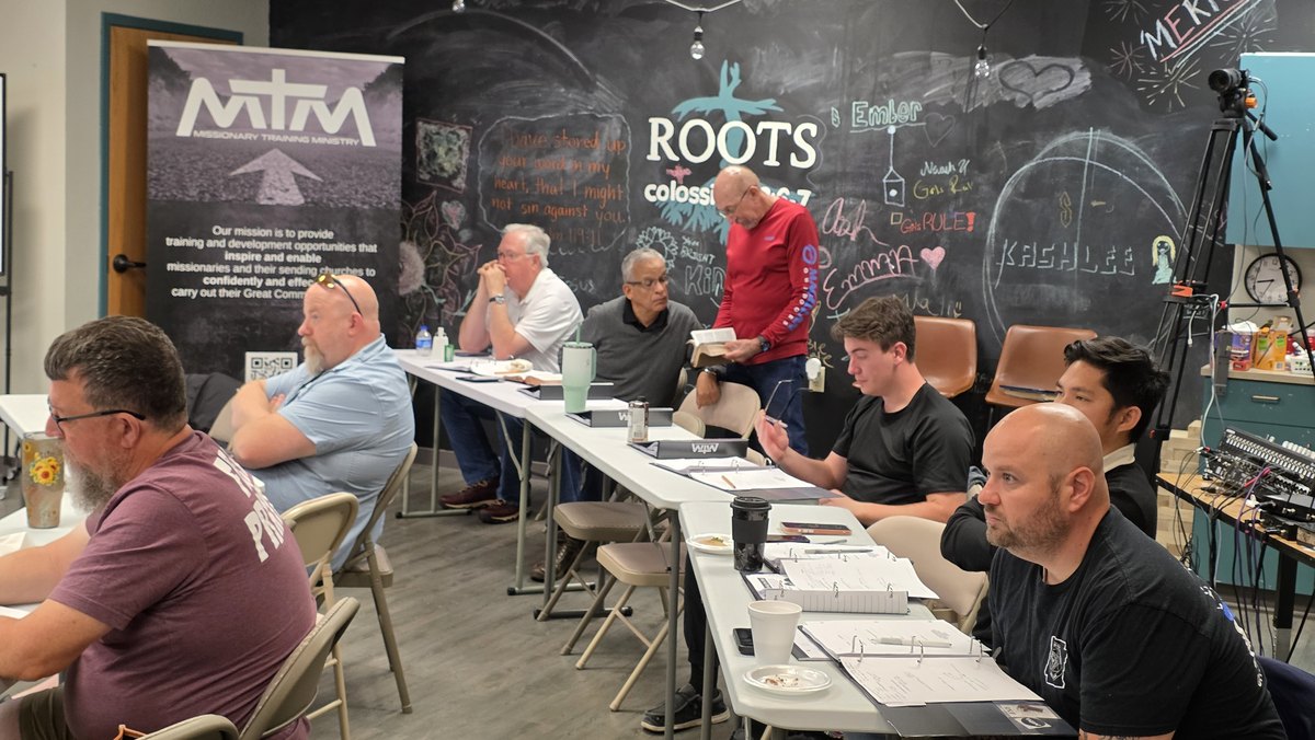 The MTM banner and ROOTS chalkboard wall behind the class